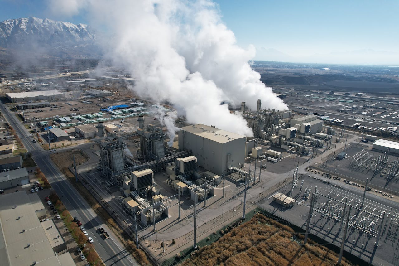 services-03 Aerial shot of an industrial plant emitting smoke in Lindon, Utah with mountains in the background.