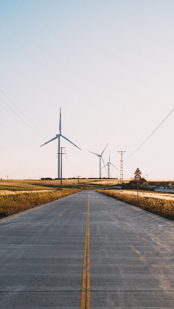 why-choose-us-02 A tranquil rural road in Silivri, Istanbul with wind turbines harnessing clean energy.
